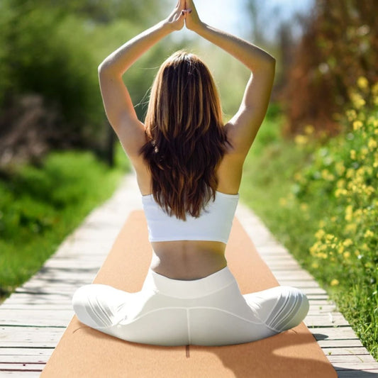 femme assise sur tapis de yoga mains jointes dessus tête