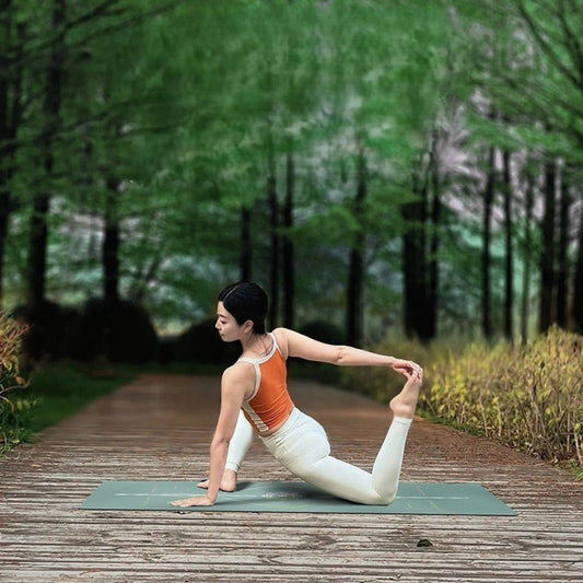 femme pied gauche dans main dans forêt sur tapis de yoga