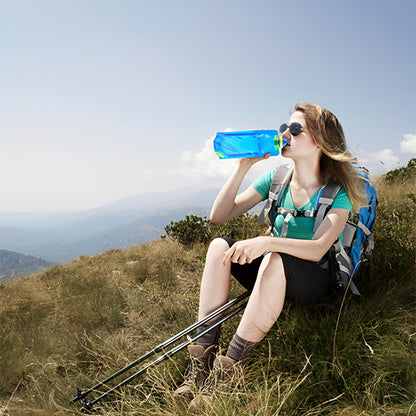 gourde souple femme boit eau assise herbe randonnee