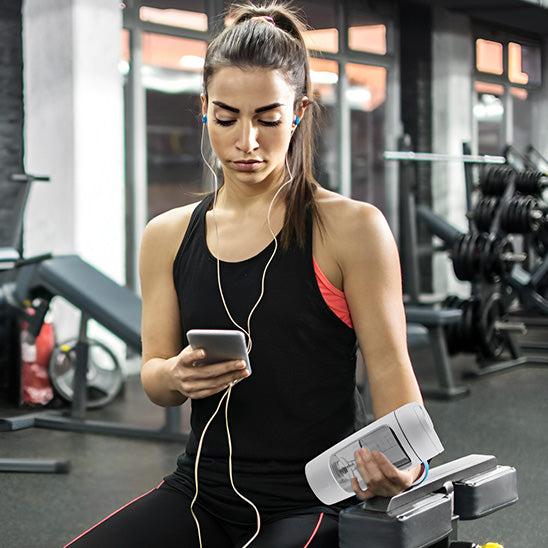 shaker dans main droite femme téléphone main gauche salle sport