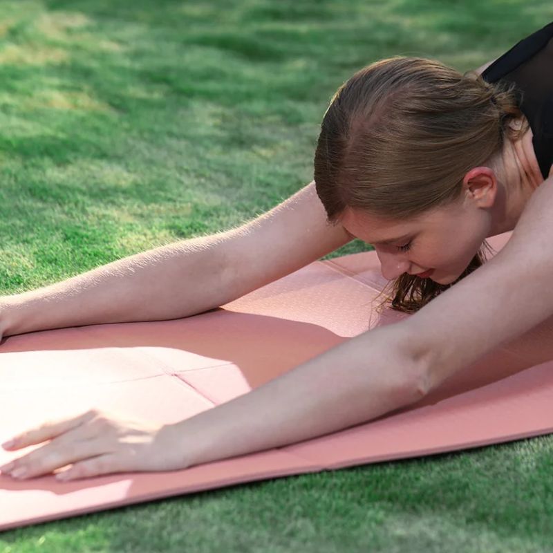 tapis-de-yoga-chakra-rose-femme-bras-allonges-devant-soi-sur-l-herbe